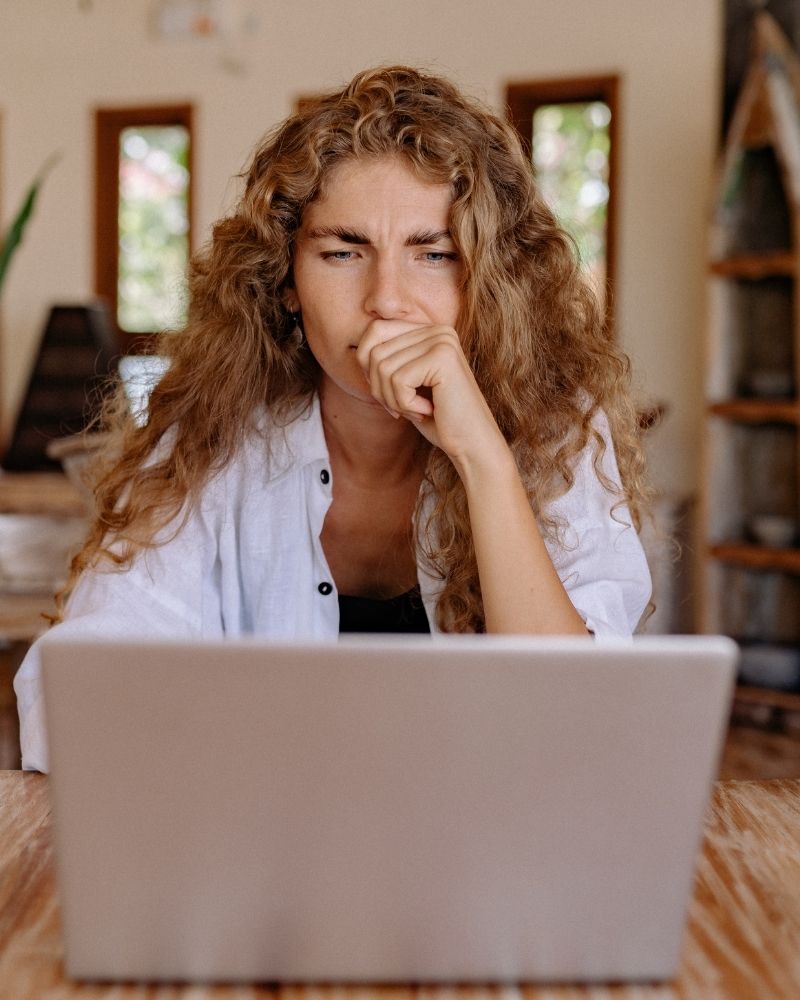 Woman looking on laptop researching clear braces for smiles club.