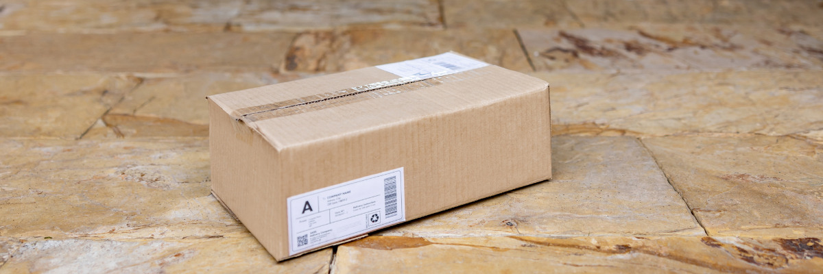A package with an invisible aligner impression kit from smiles club at the door of a house.